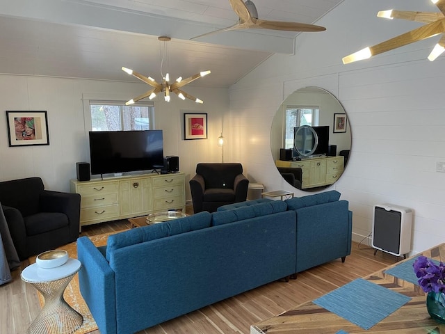 living area with ceiling fan with notable chandelier, lofted ceiling with beams, and wood finished floors