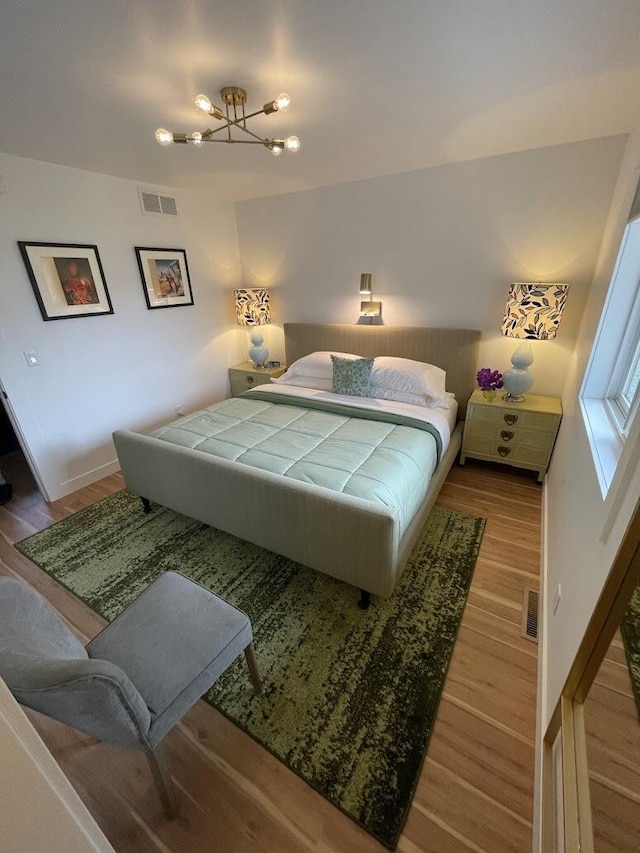 bedroom with baseboards, visible vents, and wood finished floors