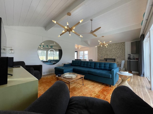 living area featuring a chandelier, light wood-type flooring, a brick fireplace, and lofted ceiling with beams