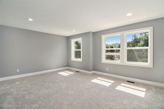 spare room with recessed lighting, carpet flooring, baseboards, and visible vents