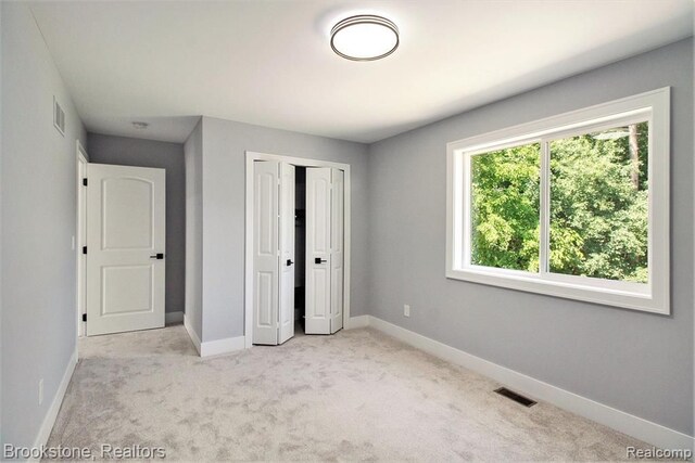 unfurnished bedroom featuring a closet, visible vents, light colored carpet, and baseboards