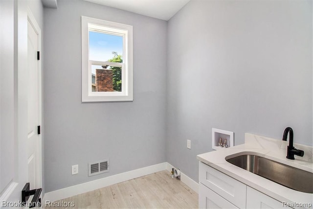 laundry room featuring visible vents, a sink, light wood finished floors, baseboards, and hookup for a washing machine