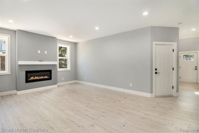 unfurnished living room with recessed lighting, baseboards, and light wood finished floors