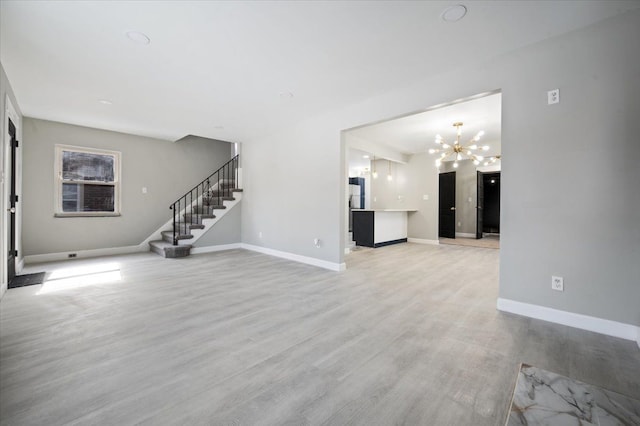 unfurnished living room with light wood-type flooring, baseboards, an inviting chandelier, and stairs