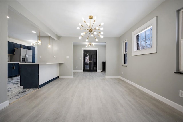 unfurnished living room with an inviting chandelier, baseboards, light wood finished floors, and beamed ceiling