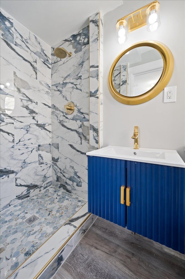 bathroom featuring wood finished floors, a shower stall, and vanity