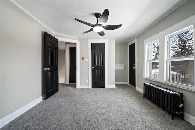 unfurnished bedroom with baseboards, a ceiling fan, radiator, ornamental molding, and carpet floors