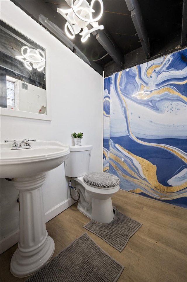 bathroom with wood finished floors, toilet, and baseboards