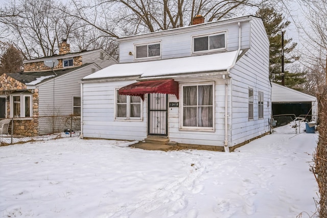 view of front facade featuring a chimney, fence, and a detached garage