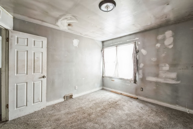 spare room with carpet flooring, visible vents, and baseboards