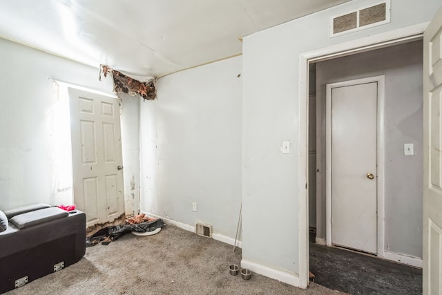 interior space featuring dark colored carpet, visible vents, and baseboards