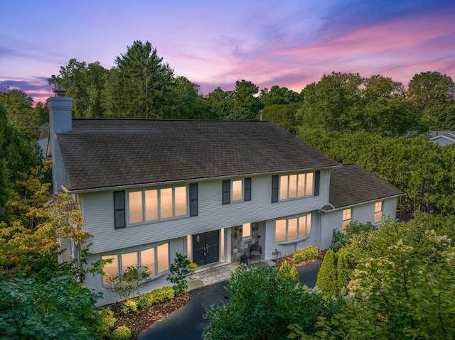 view of front of house with roof with shingles, a chimney, and a patio