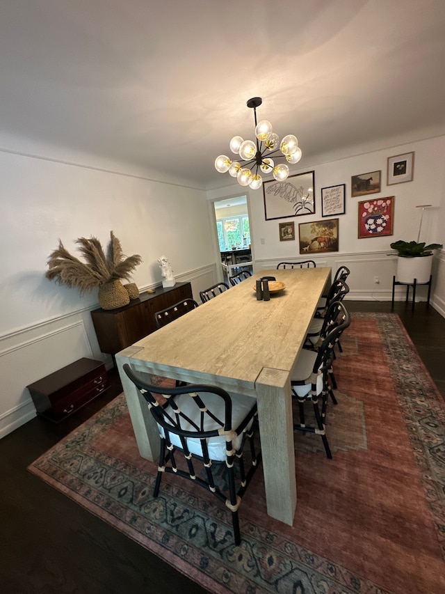 dining room featuring dark wood-style floors, a chandelier, a decorative wall, and wainscoting