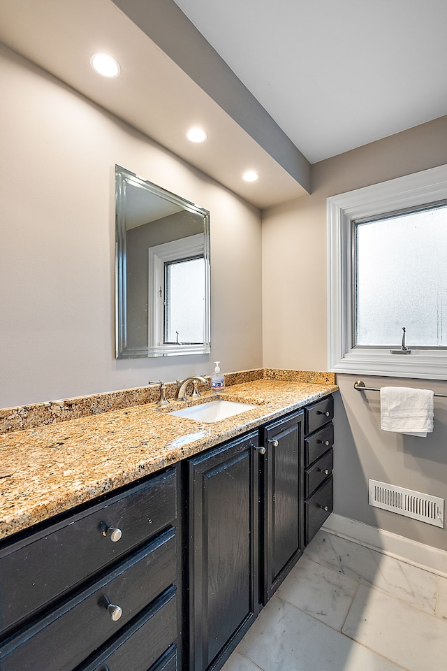 bathroom with marble finish floor, vanity, visible vents, and a healthy amount of sunlight