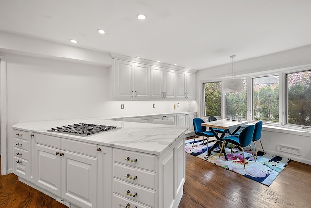 kitchen featuring light stone counters, stainless steel gas cooktop, white cabinetry, and hanging light fixtures