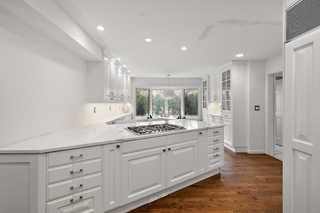 kitchen with light stone counters, decorative light fixtures, stainless steel gas cooktop, glass insert cabinets, and white cabinetry