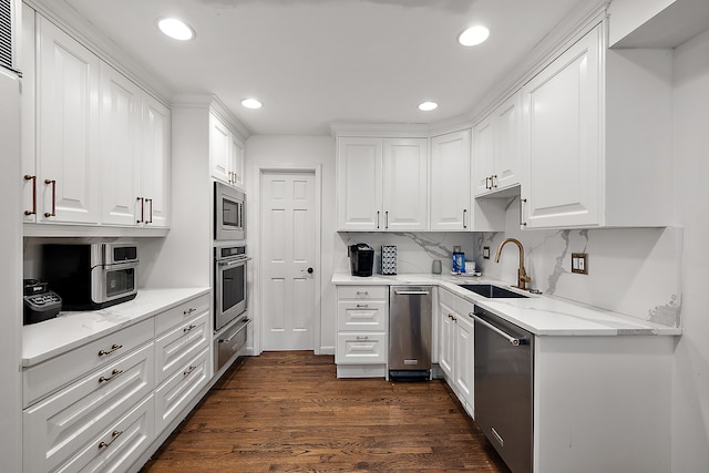 kitchen featuring light stone counters, stainless steel appliances, dark wood-type flooring, a sink, and white cabinets