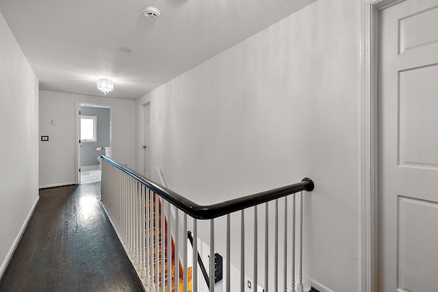 corridor featuring an upstairs landing, dark wood-style flooring, and baseboards