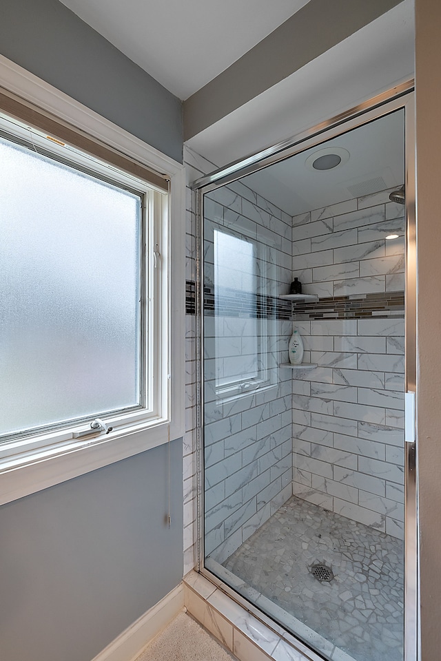 bathroom featuring a stall shower, plenty of natural light, and baseboards