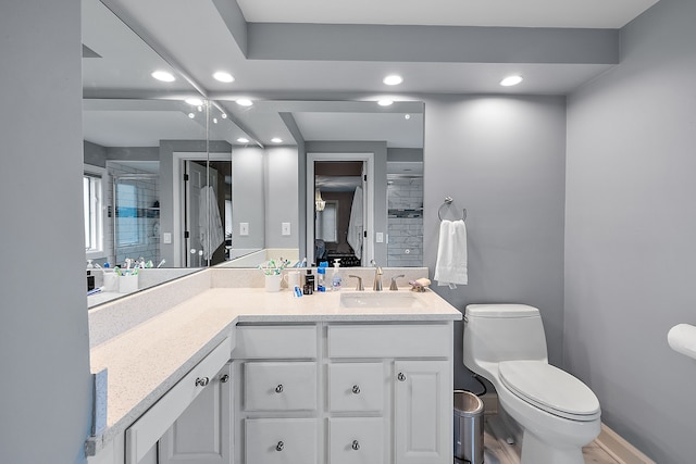 bathroom with a shower, recessed lighting, toilet, vanity, and baseboards