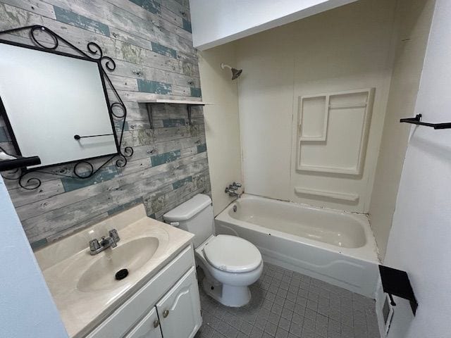 bathroom featuring toilet, tile patterned flooring, wooden walls, vanity, and shower / washtub combination