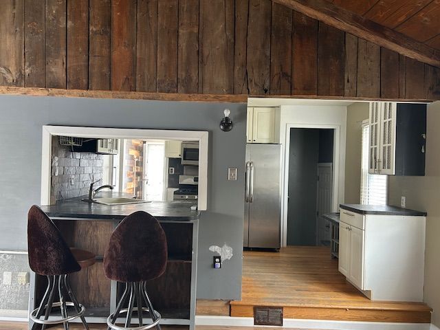 kitchen with dark countertops, appliances with stainless steel finishes, a sink, and a kitchen bar