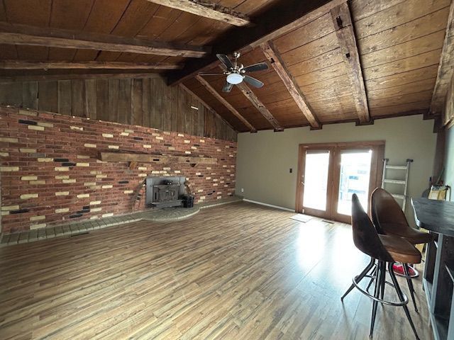 unfurnished living room featuring wooden ceiling, baseboards, ceiling fan, wood finished floors, and a wood stove