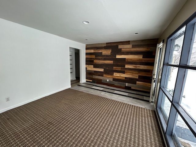 carpeted spare room with wood walls, baseboards, and recessed lighting