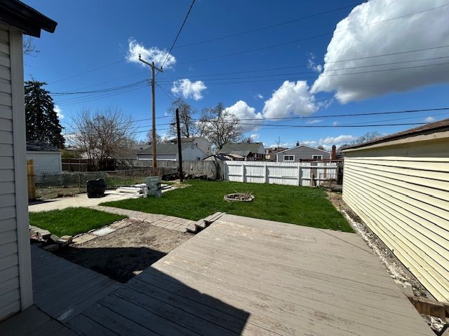 wooden deck with a yard, a fire pit, and a fenced backyard
