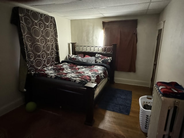 bedroom featuring a paneled ceiling, baseboards, and wood finished floors