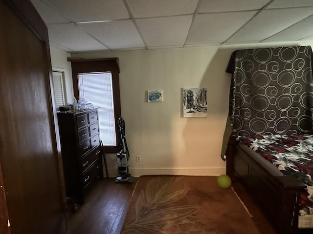 bedroom with baseboards, dark wood-style flooring, and a drop ceiling