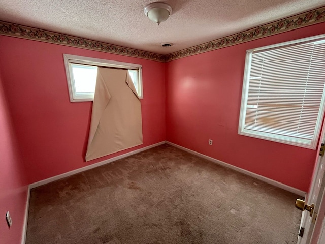 carpeted spare room featuring baseboards and a textured ceiling