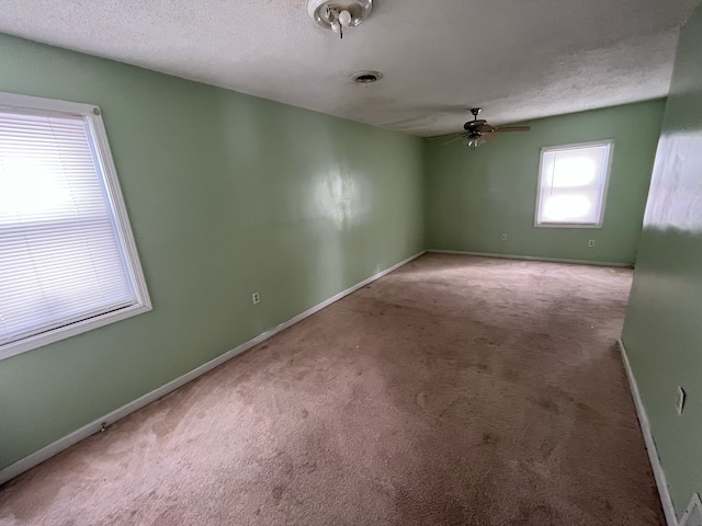 spare room featuring a textured ceiling, a ceiling fan, visible vents, baseboards, and carpet