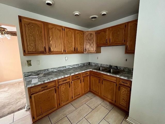 kitchen featuring light tile patterned floors, visible vents, brown cabinets, and a sink