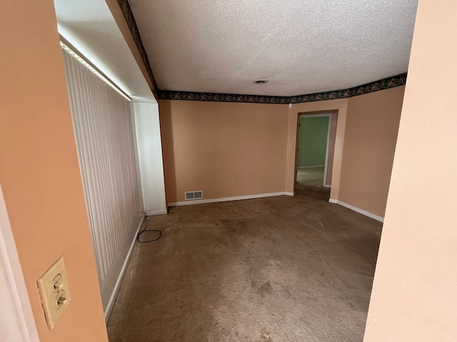 carpeted empty room featuring a textured ceiling, visible vents, and baseboards