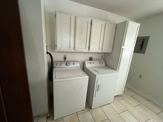 washroom featuring wood finish floors, baseboards, cabinet space, electric panel, and washer and clothes dryer