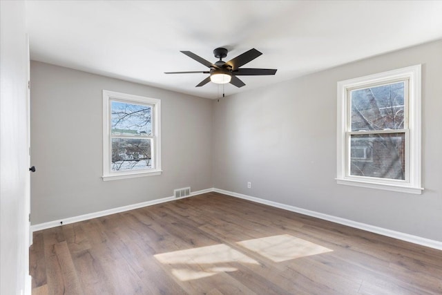 unfurnished room with a ceiling fan, baseboards, visible vents, and wood finished floors