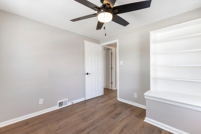 spare room with ceiling fan, baseboards, visible vents, and dark wood finished floors