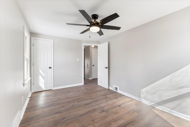 unfurnished bedroom with a ceiling fan, dark wood finished floors, visible vents, and baseboards