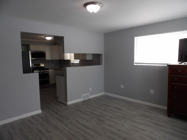 kitchen with dark wood-style flooring, stainless steel appliances, visible vents, a sink, and baseboards