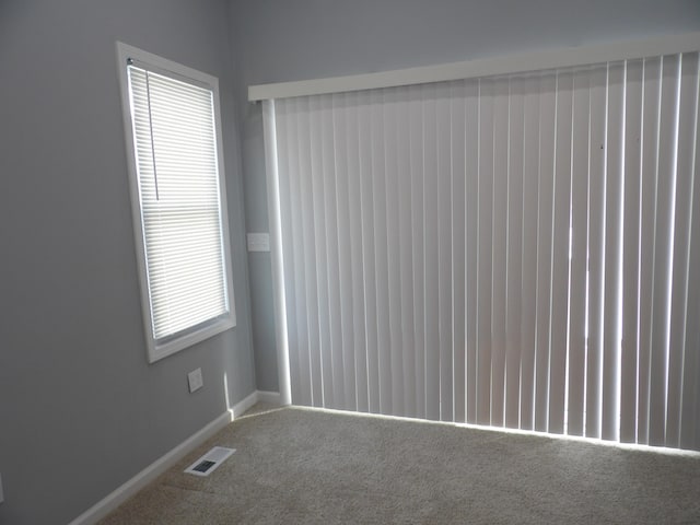 carpeted spare room featuring baseboards and visible vents