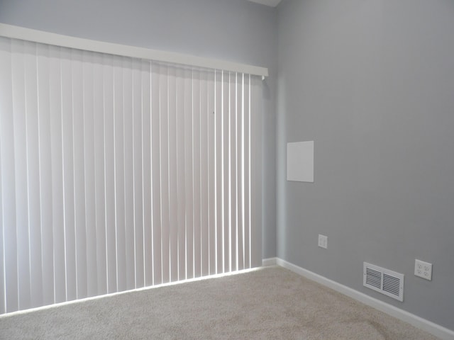 carpeted spare room featuring baseboards and visible vents