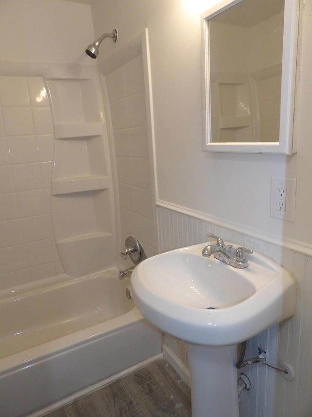 bathroom with a wainscoted wall, wood finished floors, and bathtub / shower combination