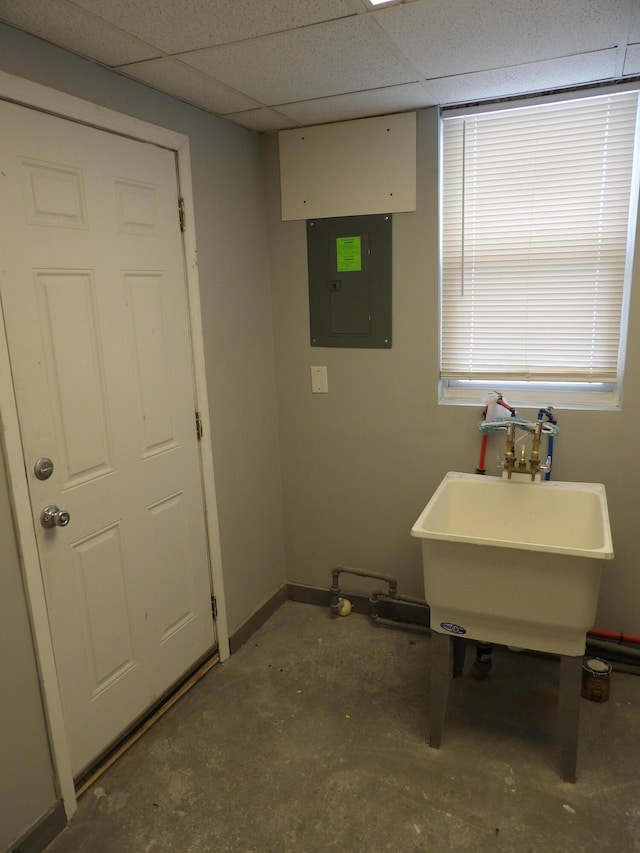 interior space with electric panel, a sink, and baseboards