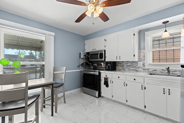 kitchen featuring decorative backsplash, marble finish floor, stainless steel appliances, white cabinetry, and a sink