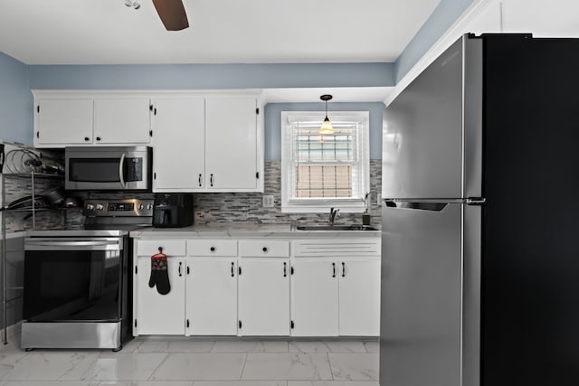 kitchen featuring marble finish floor, stainless steel appliances, light countertops, white cabinets, and a sink