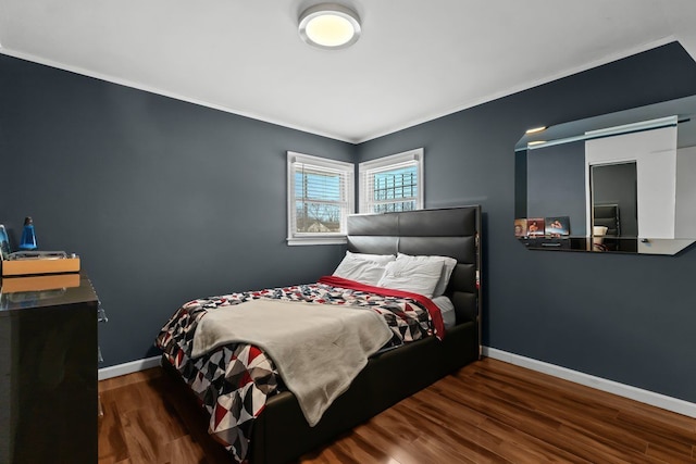 bedroom featuring ornamental molding, baseboards, and wood finished floors