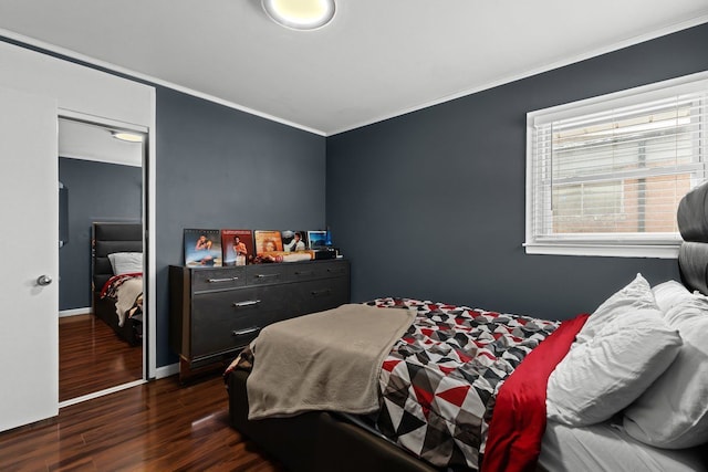 bedroom featuring dark wood-style floors, a closet, baseboards, and crown molding