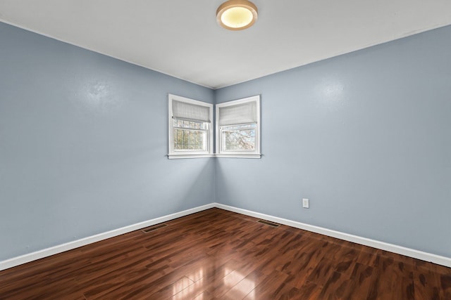 empty room featuring visible vents, baseboards, and wood finished floors