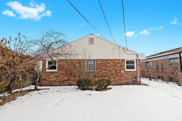 snow covered back of property featuring brick siding